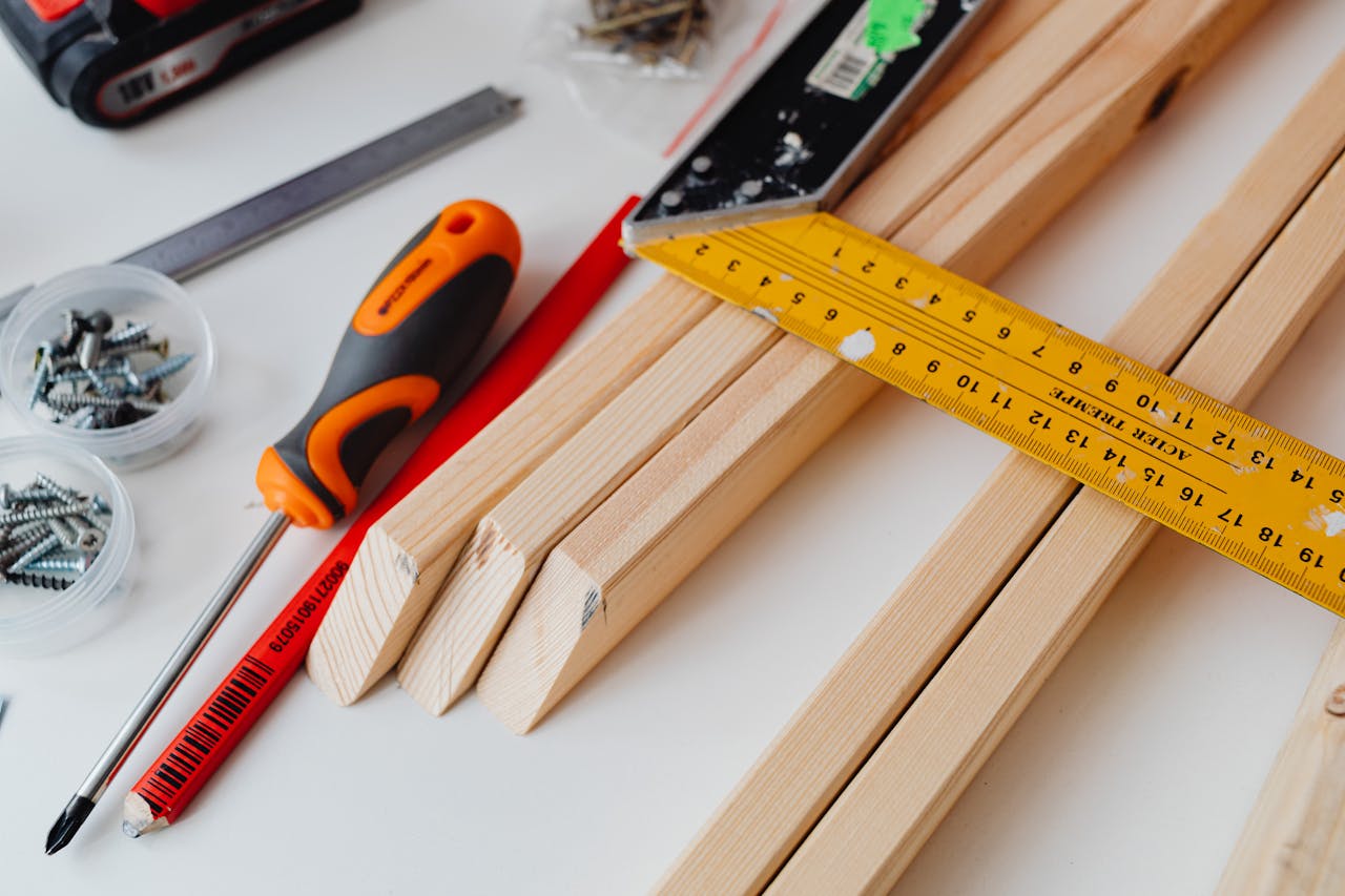 Home A variety of tools including screws, screwdriver, and ruler on a woodworking table.